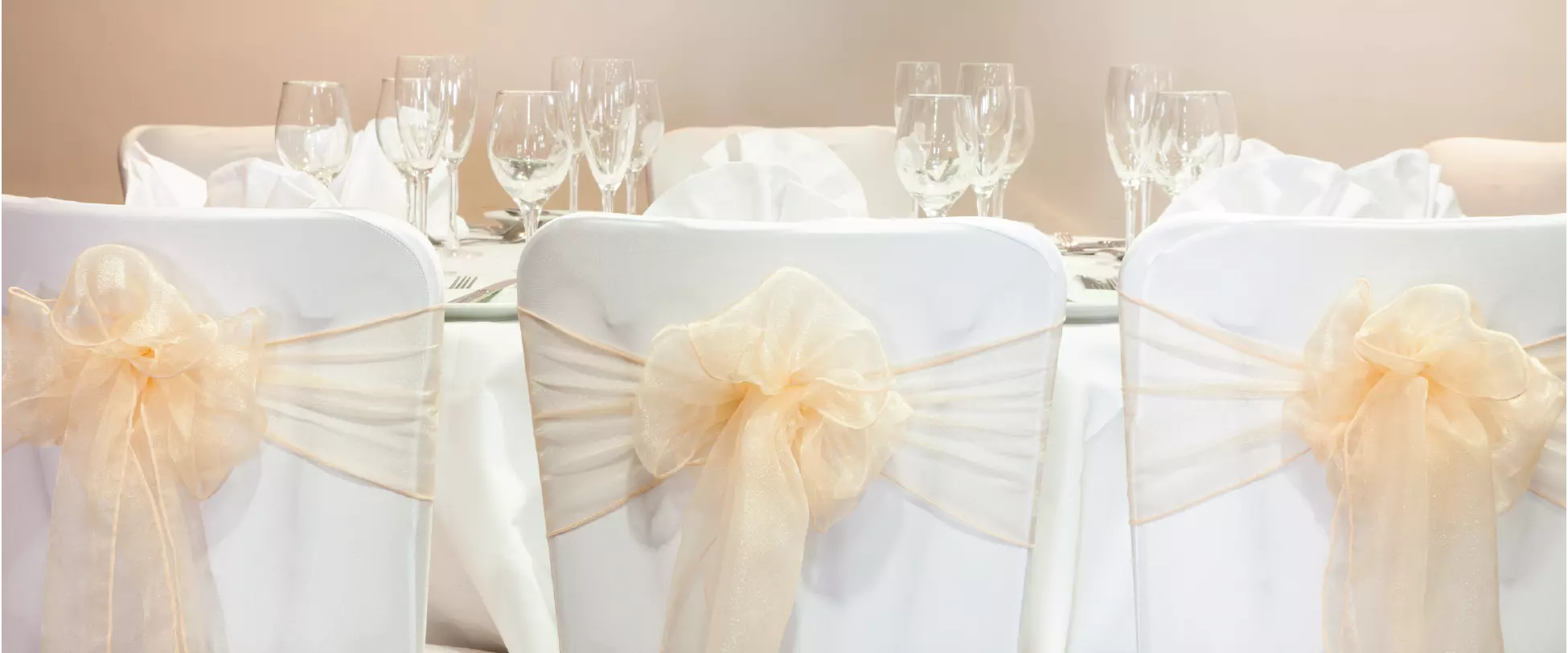 Chairs set up for a wedding breakfast with white covers and yellow ribbons.